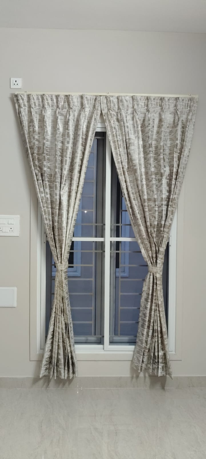 Grey patterned curtains, tied back